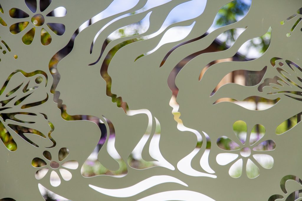 Image of laser cut screens green in colour with a cut out of 3 women's head and shoulders.
