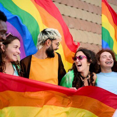 Group of excited young friends enjoying together on gay pride day. Joyful people gathered lgbti.